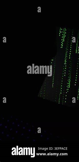Glowing green digital code falls down a dark computer screen monitor. A modern keyboard with purple illuminated keys rests blurred in the foreground. The dark setting feels futuristic Stock Video Footage - Alamy
