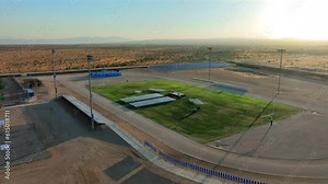 High School graduation set up on the campus football field for the ceremony at sunset - aerial