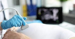 Doctor conducts ultrasound examination of abdomen of young pregnant woman in modern clinic