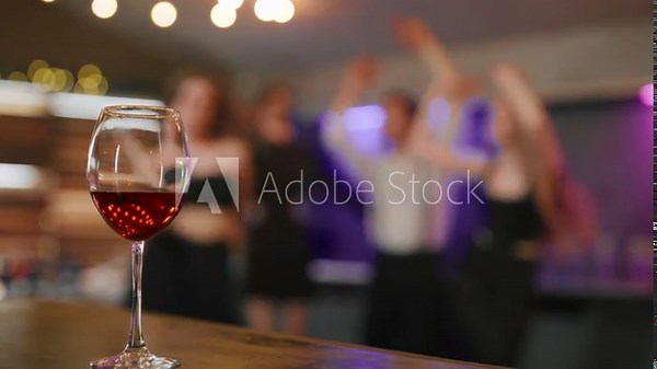 Close-up of cocktail drink in club. Banquet table with glass of alcohol cocktail on party background with silhouettes of people dancing on the dance floor. Party, event, have fun, clubbing concept.