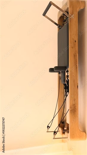 Close up of a Pilates Reformer trainer made from wood and metal showing detailed construction and features of one of the most popular and effective machines used for Pilates workouts