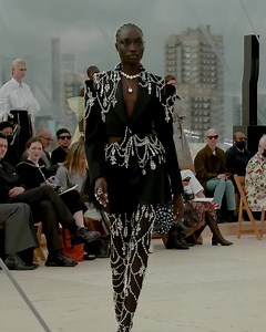 At the #McQueenSS22 show, Nyagua wearing a single-breasted tailored tuxedo jacket with slashed shoulders and waist, satin lapels, crystal raindrop embroidery and a black Paris net cloud back in black wool. Worn with crystal raindrop embroidered Arc boots. Watch the show: on.alexandermcqueen.com/SS22Show_AMQ | Alexander McQueen