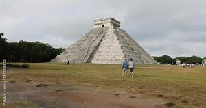 Chichen Itza couple walk towards El Castillo pyramid. Pre Columbian city built by the Maya people in Yucatan, Mexico. One of the largest Maya cities. Most visited archaeological sites in Mexico.