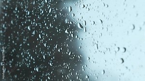 Snow fall on window and melting into water drops on glass in the forest. Large rain drops strike window during winter shower. Pure rain drops. Vertical.