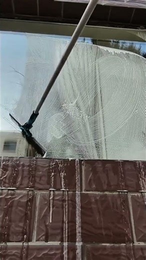 cleaning a glass window using a squeegee tool for professional outdoor maintenance activity