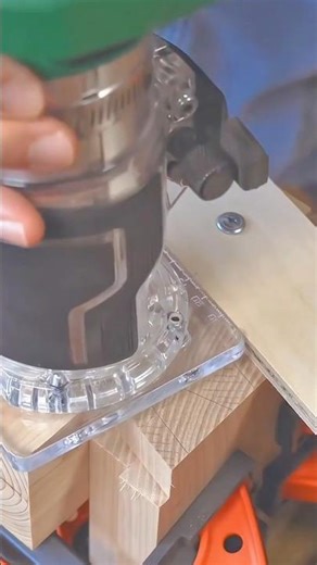 Woodworker using a handheld trim router to shape and profile the edge of a wood joint