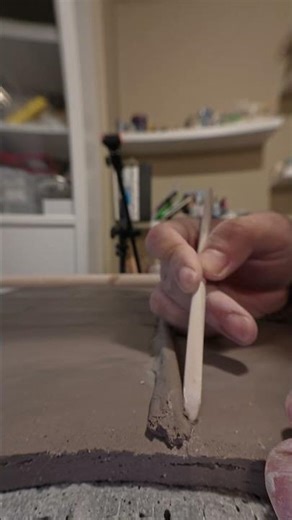 Pressing a clay coil onto a slab using fingers and a wooden tool for support.#ceramics #stoneware