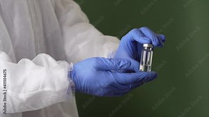 Science matters. Lab assistant in personal protective equipment or PPE suit holding a vial of new vaccine, posing isolated over green screen background. Science, Covid19 and healthcare concept