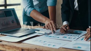 Business people collaborating, using calculators and analyzing financial reports in a modern office environment