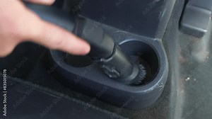 Man hands using vacuum cleaner to clean dirty car interior. Cup holders in close up. Car service worker uses vacuum cleaner