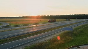 Russian logging trucks, two timber lorry hauling forest logs on semi-trailer on countryside highway at sunset. Commercial Timber Transport. Tractor full of trees wood. Import export. Delivery vehicle