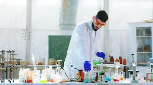 Chemical reaction in a biotechnology laboratory man using some blue liquid to make a experiment and analyzing the reaction he wearing protective equipment