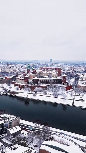 Winter turned Wawel into a storybook scene ❄️ The cathedral towers rise above the city like frozen guardians 🏰 Crowds move along the pathways, chasing the charm of the cold rather than escaping it 🚶‍♂️ Red rooftops clash beautifully with the thick snow blanket 🌨️ Trees shimmer like crystal around the fortress walls 🌲 The modern skyline in the distance reminds you that history is still alive here 🌆 A moment when Krakow feels cinematic, calm and unforgettable - the kind of view that stops you
