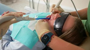 Close up Woman Dentist and Assistant Uses Modern Equipment to Treat Teeth on Female Patient in Dental Clinic. Medicine and Health Concept. Treatment Toothache. Slow Motion.