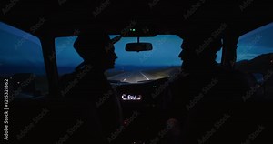 Young couple kissing in the front seats of their car driving through the night on a road trip while. headlights cutting through the darkness and illuminating the winding road ahead, embracing the