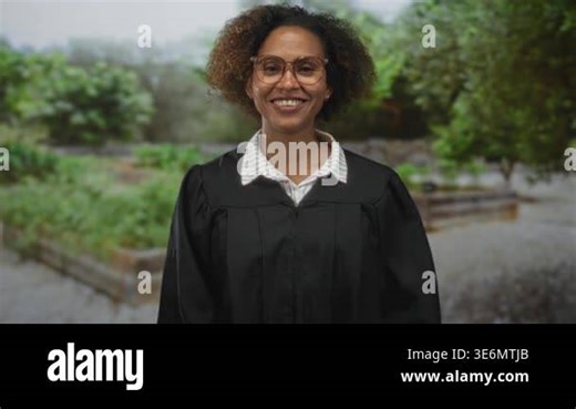 Woman judge in black robe smiling and holding hands to head with glasses in a green park forest setting; joy celebration achievement Stock Video Footage - Alamy
