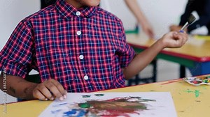 African kid painting during art class in kindergarten class room. Multiracial children students and school education