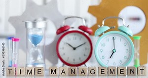 The inscription time management on wooden cubes against the background of alarm clocks, close-up. The concept of increasing efficiency