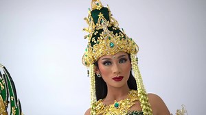 Traditional Indonesian dancer in ornate costume with headpiece, performing cultural dance.
