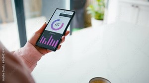 Close up of woman drinking coffee looking at sleep tracking app on mobile phone at home - shot in slow motion