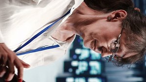 Vertical video Octogenarian system administrator working in data center housing GPU dedicated server rigs that can process AI tasks with high efficiency, fixing out of order devices used for machine