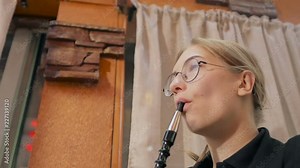A young girl sitting in a cafe smoking a hookah, slowly exhaling thick white smoke.