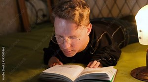 a man with disabilities reads a book lying on the bed