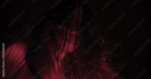 A woman ghost with hair over their face with wind blowing illuminated by a red light creating a haunting effect. Halloween holiday