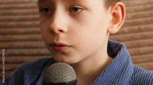 portrait of a caucasian boy of school age singing into a microphone. the child sings into a karaoke microphone. vocal lessons at home. distance learning vocals. creative musical abilities in children