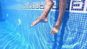 4K video beautiful human legs shaking water in swimming pool. Relax and vacation concept