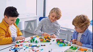 Robotics programming class. Children construct and code Robot. STEM education using constructor blocks and laptop tablet, remote control joystick. Technology educational development for school kids