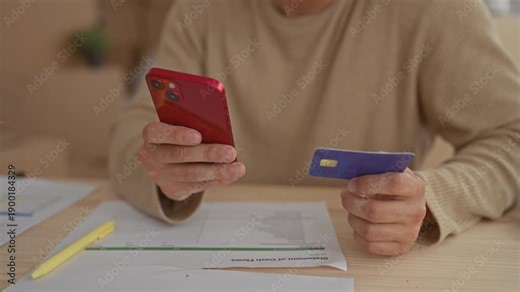 Man steers hands by holding phone next to card inside home as young hispanic movers bring moving boxes ready for unpacking by male helpers.