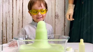 Scientific experiment at home, as a result there are form a lot of foam. Laboratory tests for pre-school homework. Mother with son kid making chemical test at home. High quality 4k footage