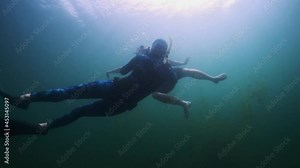 Underwater photography with model. Woman swims underwater with professional camera housing in the freshwater lake and takes pictures of the male model