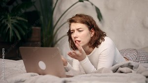 Irritated arguing young woman yelling at laptop computer while laying on bed at home Angry nervous female talk by video call expressing negative emotion Bad conflict working or personal conversation