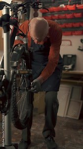 Old man Bicycle mechanic in workshop in repair process installing wheel