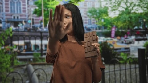 clip-4030831269-hispanic-young-brunette-woman-holding-chocolate-bar