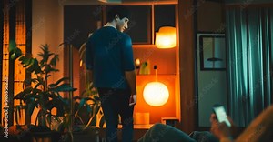 two friends talk in the living room while one chats on his cell phone