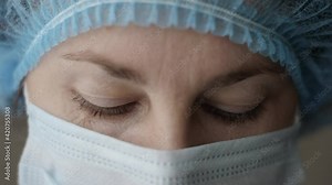 Sad Sick, Overworked Serious Female Health Care Worker Downs Eyes Looking at Camera. Portrait Close Up Doctor Nurse Wearing Protective Mask, Protection Against Contagious Corona Virus Disease COVID-19