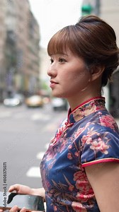 Vertical video of a Taiwanese woman in her 20s wearing a blue traditional Chinese dress walking on the crosswalk in the historical district Bopiliao Historic Block, Wanhua District, Taipei City, Taiwa