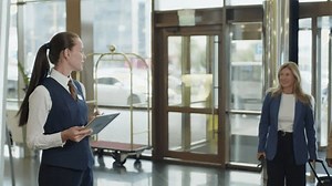 clip-3417042757-female-hotel-manager-standing-lobby-checking-reservation