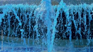 Abstract blue water flows and splashes of decorative dyed fountain. Colored liquid streams falling in slow motion close up
