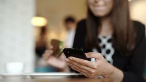 Young woman eats sandwich in cafe while texting - Free Stock Video