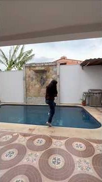 girl jump in the pool fully clothed wearing hoodie, jeans and shoes