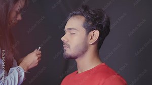 Make up artist preparing man's face for prosthetic inserts for Halloween mask by drawing a lines where inserts must be applied
