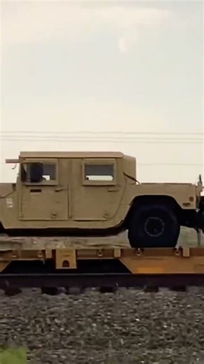 Rapidly passing military railroad train hauling multiple different types of Humvee vehicles