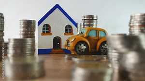 coin stack with mini car and home on the table, panning video