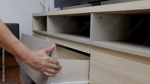 Handyman fixing over tight drawer slides of TV shelf. Concept Fix stuck wooden drawer slides.