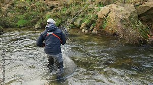 slow motion fisherman catches and lands rainbow trout fish caught in river