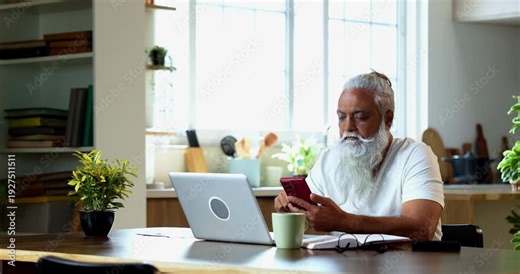 Indian mid age man expressing frustration while share market loss at home, stylish bearded trader showing thumbs down using smartphone and laptop during online trading session in modern interior
